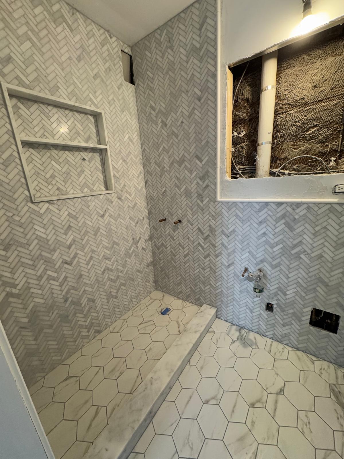 Herringbone tile shower walls with a built-in bench.