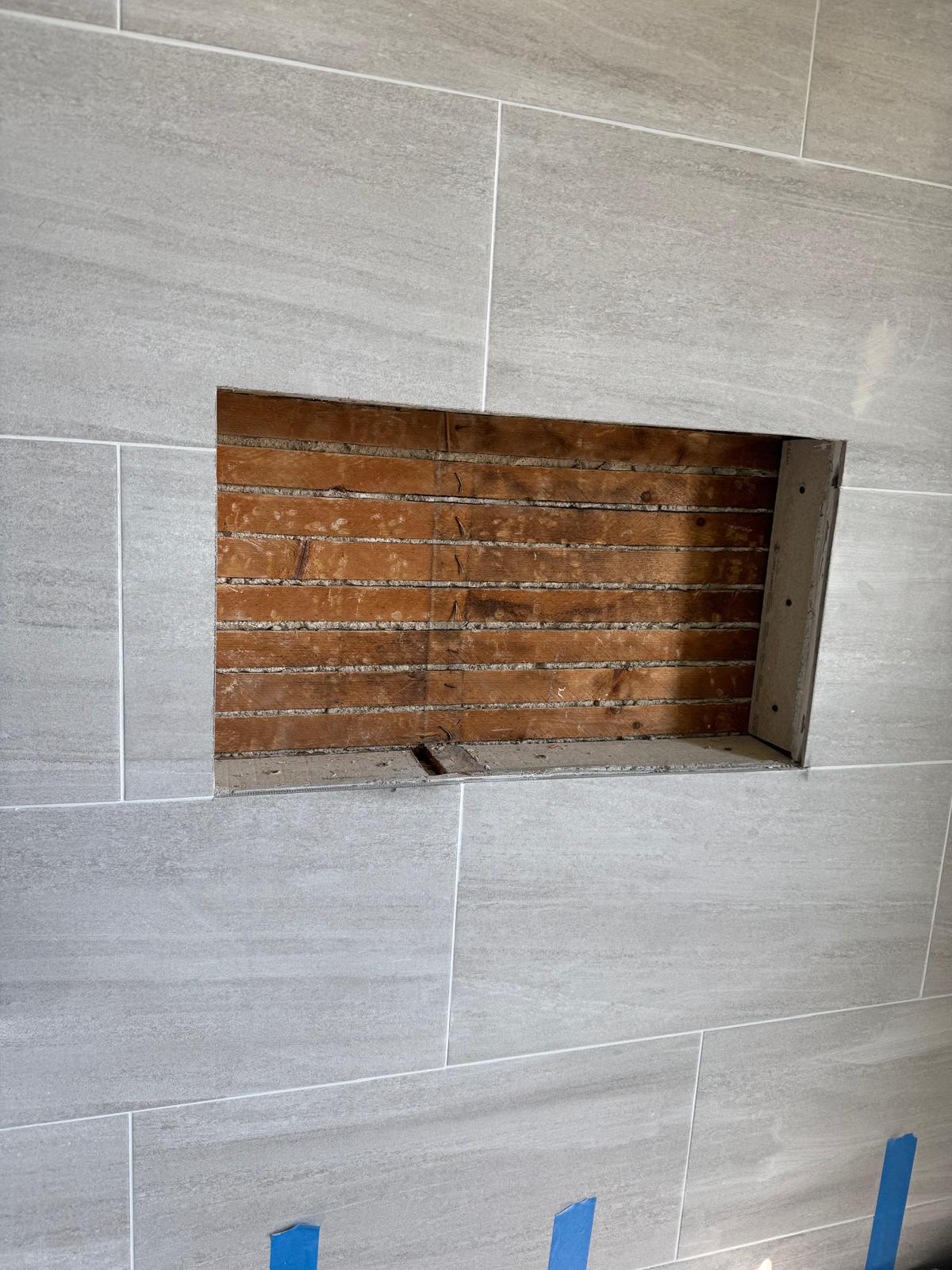 Finished shower enclosure with marble-look tile and hex floor.