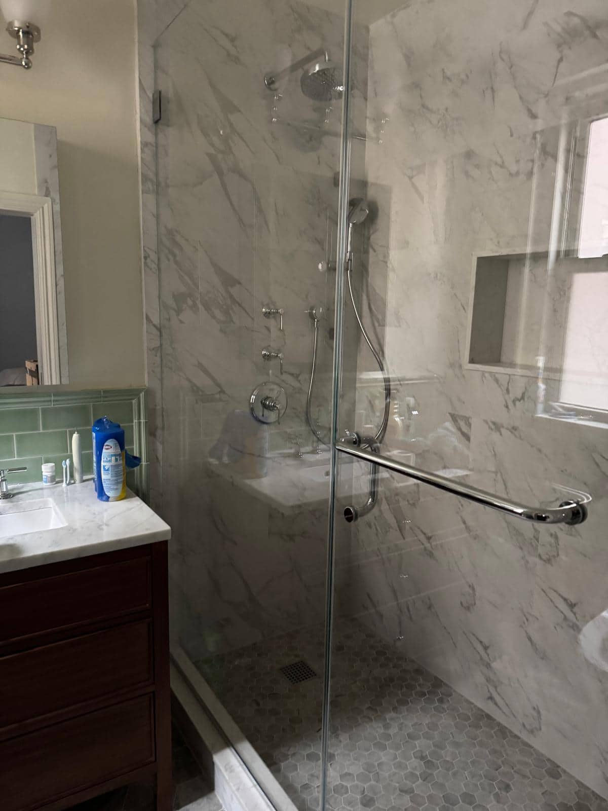 Shower with marble look tile, a recessed niche, and a glass enclosure.